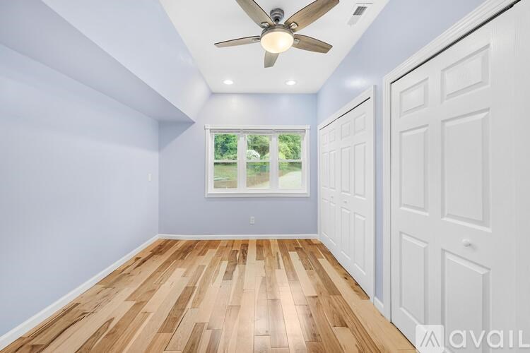 A room with a ceiling fan and wooden flooring.