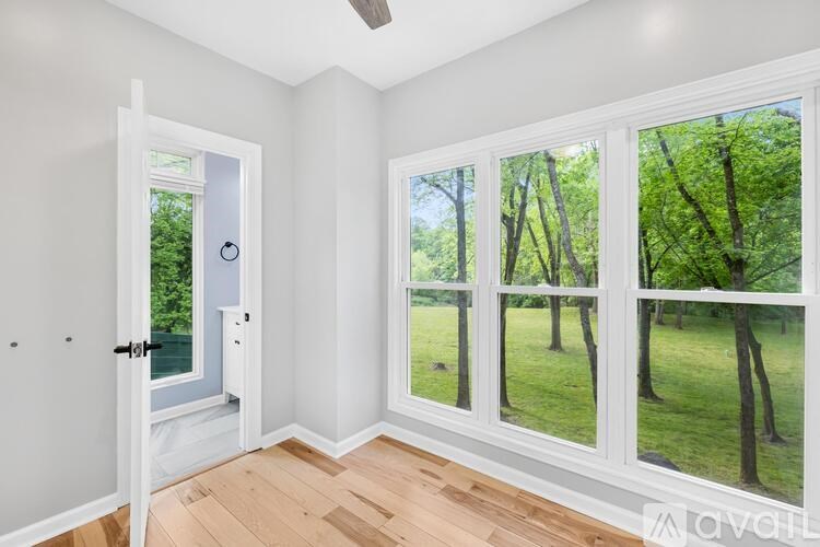 A room with a view of a green lawn and trees through the windows.