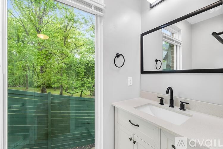 A bathroom with a large window and a white sink.