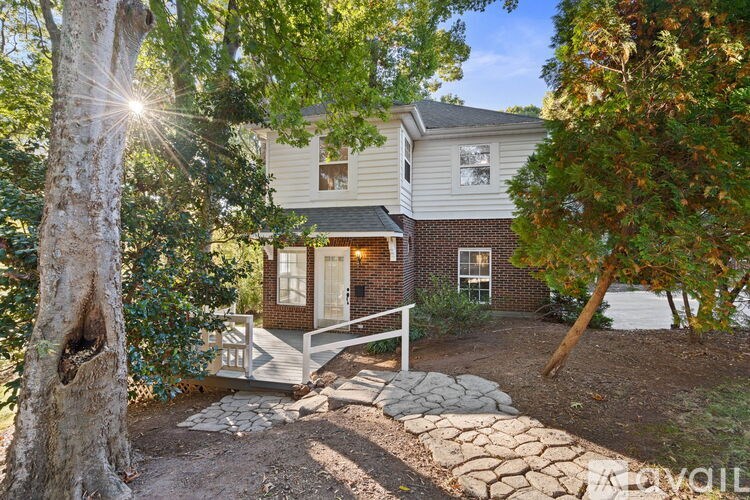 A house with a front yard and a tree in the foreground.