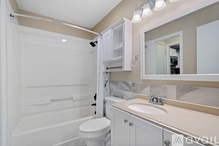 A white bathroom with a toilet, sink, and shower.