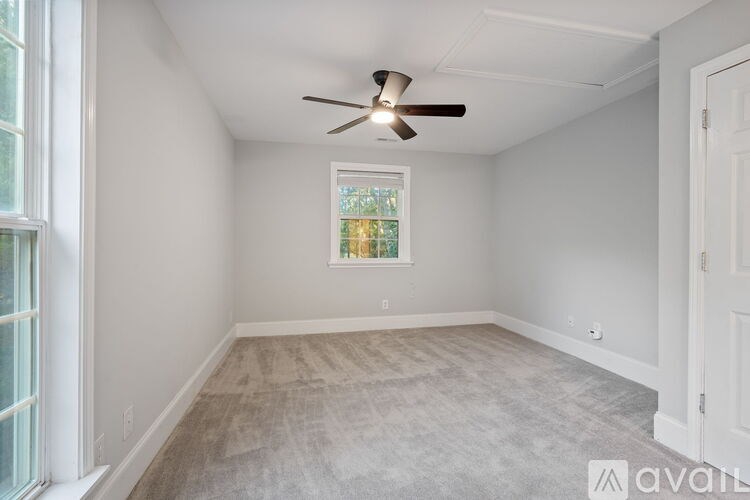A room with a ceiling fan and a window showing a tree outside.