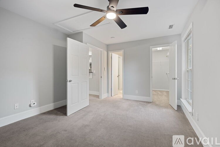 A spacious room with a ceiling fan and carpeted floor.