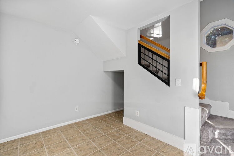 A spacious room with a window, a staircase, and a tiled floor.