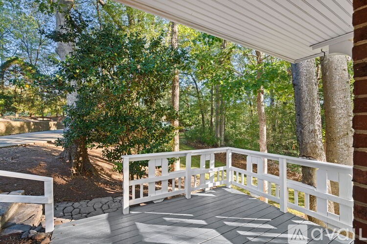 A wooden deck with a white railing overlooks a wooded area.