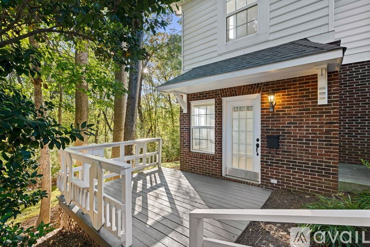 A white house with a porch and a tree in front.