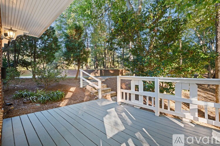 A wooden deck with a white railing overlooks a wooded area.