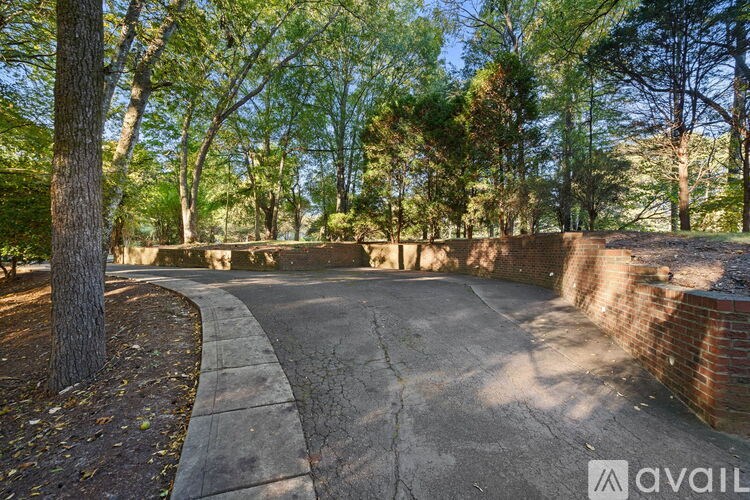 A concrete pathway in a park with trees on either side.