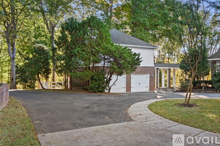 A house with a driveway and trees in front of it.