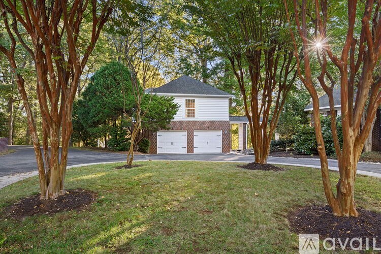 A house with a white garage door is surrounded by trees.