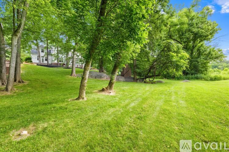 A grassy area with trees and a house in the background.
