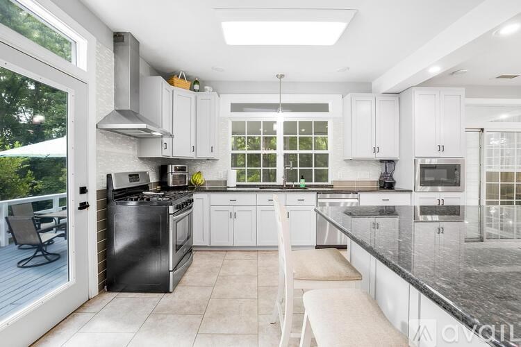 A modern kitchen with white cabinets and a black stove top oven.