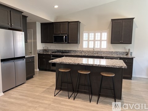 A kitchen with a granite countertop and bar stools.