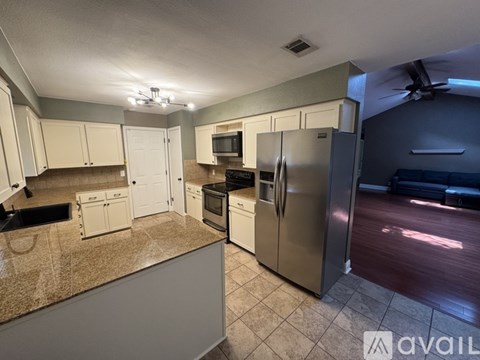 A kitchen with a refrigerator, microwave, oven, and sink.
