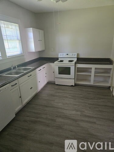 A kitchen with white cabinets and a white stove top oven.