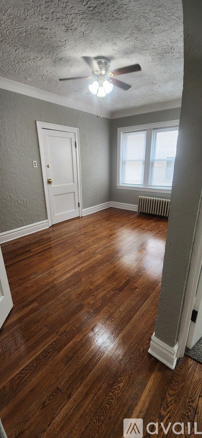 A room with a ceiling fan and wooden flooring.