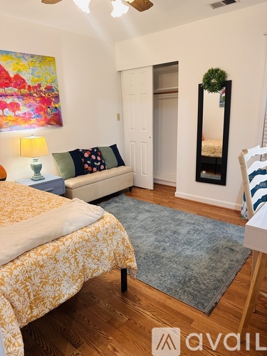 A bedroom with a bed, a couch, and a painting on the wall.