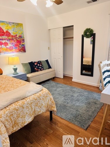 A bedroom with a bed, a couch, and a painting on the wall.