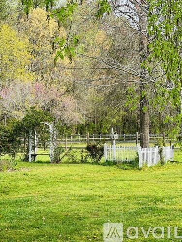 A white fence in a grassy field with trees in the background.