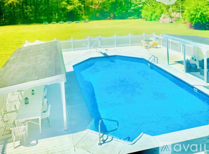 A pool with a white fence and a white table with chairs.