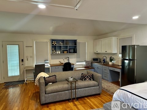 A modern living room with a grey couch and a kitchen area in the background.