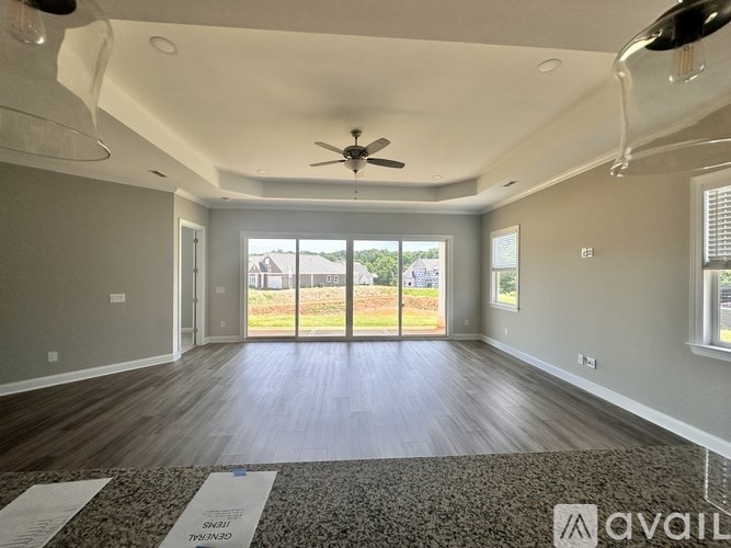 A spacious room with a ceiling fan and sliding glass doors leading to a backyard.