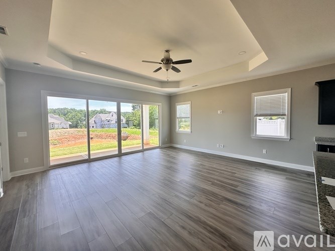 A spacious room with a ceiling fan and sliding glass doors leading to a view of a residential area.