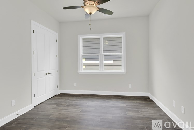 A room with a ceiling fan and a window with blinds.