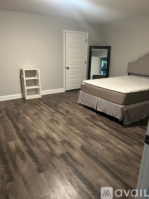 A bedroom with a bed and a wooden floor.