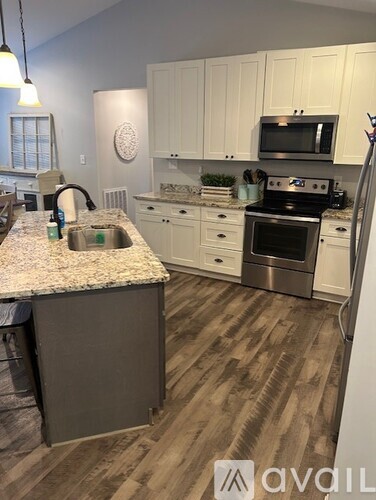 A kitchen with a granite countertop and wooden flooring.