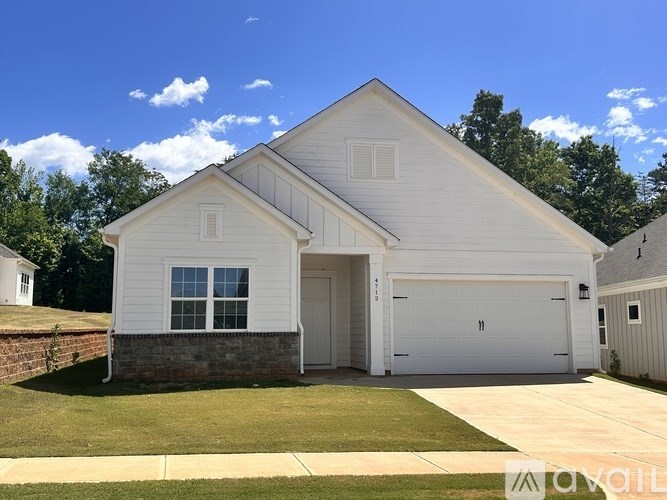 A white house with a garage door and a brick wall.