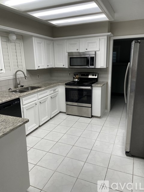 A kitchen with white cabinets and a refrigerator.
