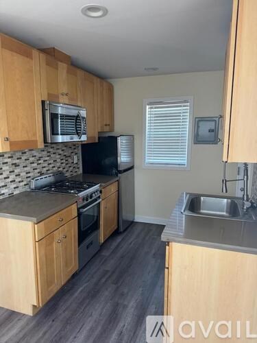 A kitchen with wooden cabinets and a black refrigerator.