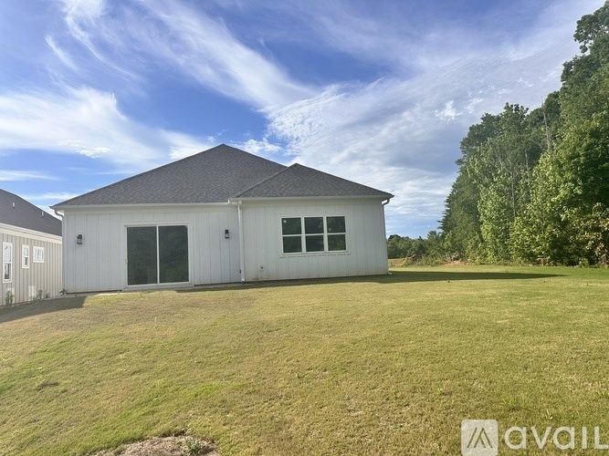 A white house with a grey roof and a large lawn in front.