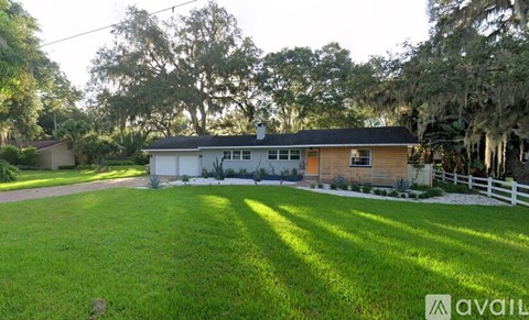 A house with a white fence and green lawn in front.