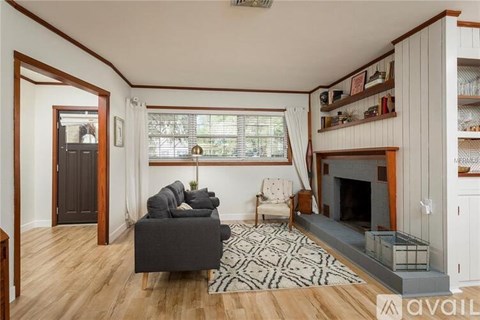 A living room with a grey couch and a fireplace.