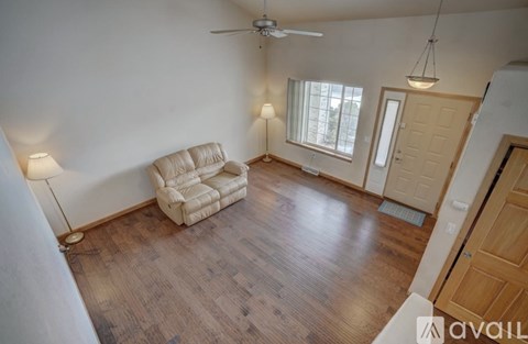 A living room with a beige couch and a ceiling fan.