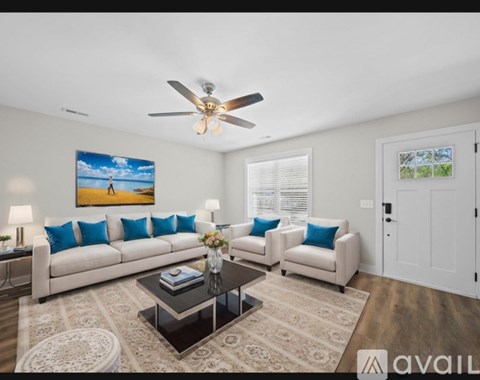 A living room with a white couch, a coffee table, and a painting on the wall.