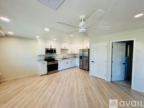 A spacious kitchen with white cabinets and a wooden floor.