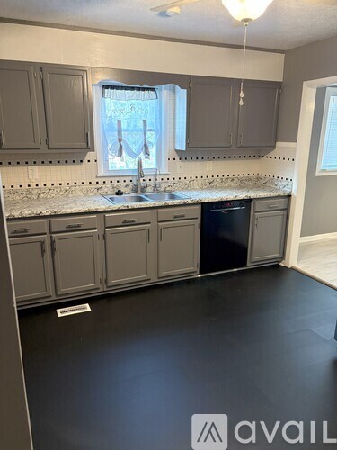 A kitchen with grey cabinets and a marble countertop.