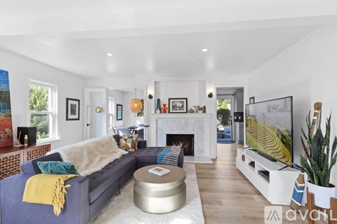 A living room with a grey couch and a white fireplace.