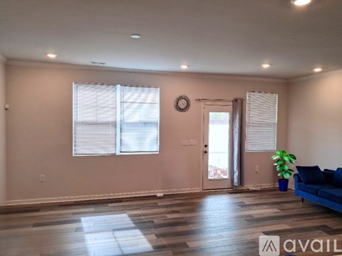 A living room with a blue couch and a wooden floor.