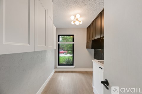 A kitchen with white cabinets and a window overlooking a parking lot.