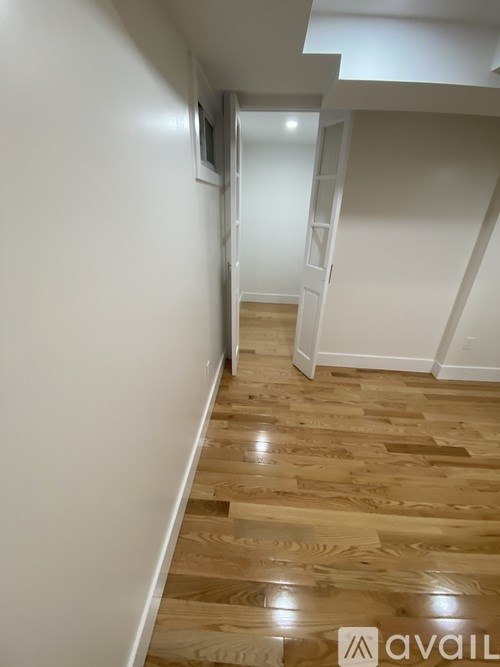 A hallway with wooden floors and white walls.