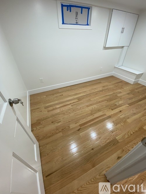 A room with wooden flooring and white walls.