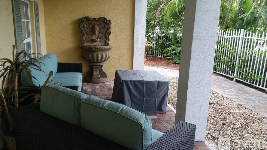 A patio with a couch, table, and a fence.