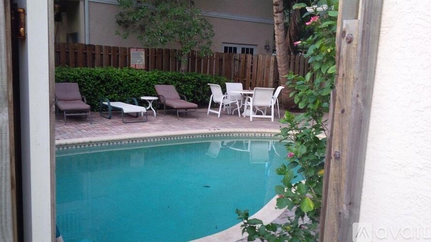 A pool surrounded by chairs and plants.