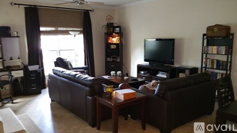 A living room with a brown leather couch and a television on a stand.