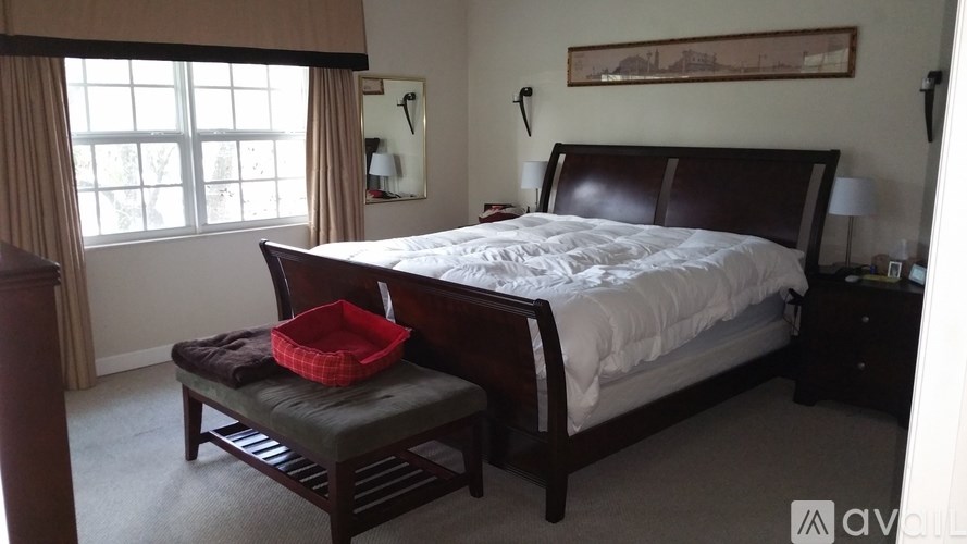 A bedroom with a large bed and a window with curtains.