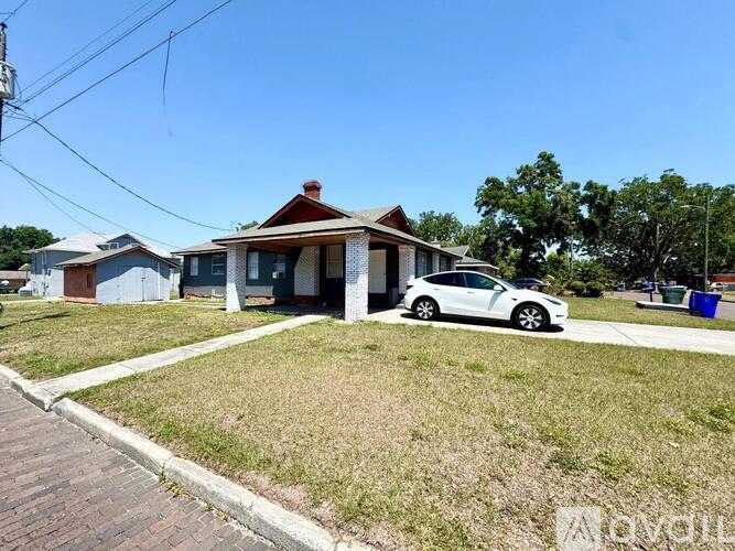 A white car is parked in front of a house.